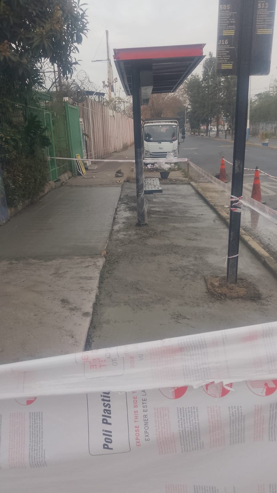 Vereda de hormigón recién vaciada junto a un paradero en obra